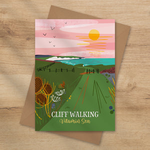 Card with a scenic illustration of a coastal cliff path and sunset with the seven sisters cliffs and the sea in the background. Cliff walking vitamin sea card by onneke