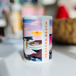 Mug with a colourful design of a seagull on Seaford Beach eating an ice cream with Seaford head cliffs in the distance.