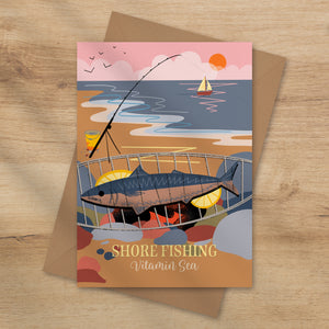 A fish on the barbeque on the beach with a fishing rod in the back ground, a sailing boat and the setting sun. Shore fishing vitamin sea greeting card by onneke