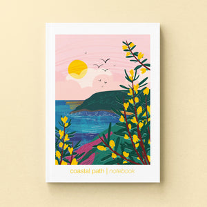 Illustrated notebook cover with a coastal scene, yellow flowers, and a pink sky.