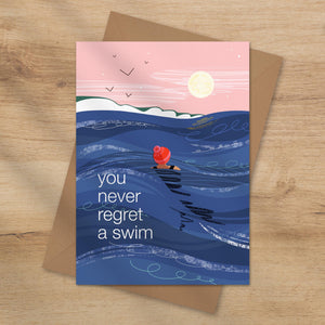 Greeting card with a swimmer in the ocean and text 'you never regret a swim' 