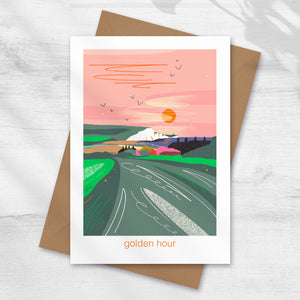 Greeting card with a scenic illustration and 'golden hour' text, the seven sister cliffs and the coastguard cottages by cuckmere haven illustrated by onneke
