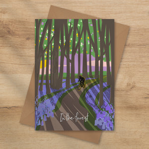 Card with a forest design featuring a cyclist and the text 'In the forest' with blue bells on the forest floor illustration by onneke
