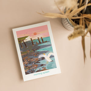 Greeting card with a seagull in the shoreline, a pebble beach and cliffs in the background. Nature illustration on coastal card by onneke