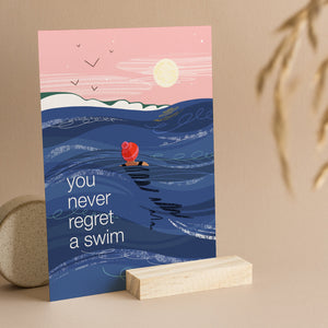 Greeting card with a swimmer in the ocean and text 'you never regret a swim' 